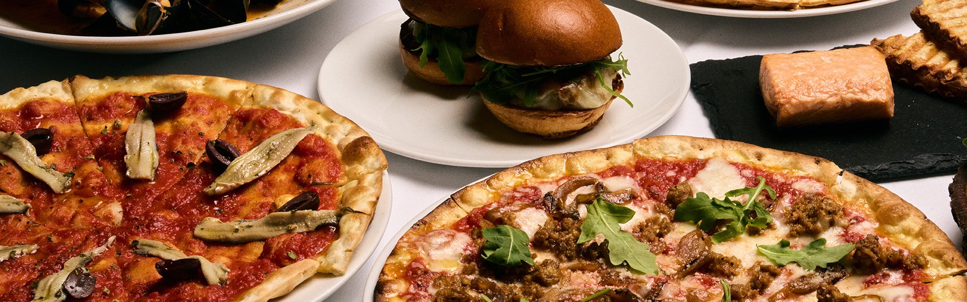 Assortment of pizza's, sliders and clams from the bar menu at Drago centro